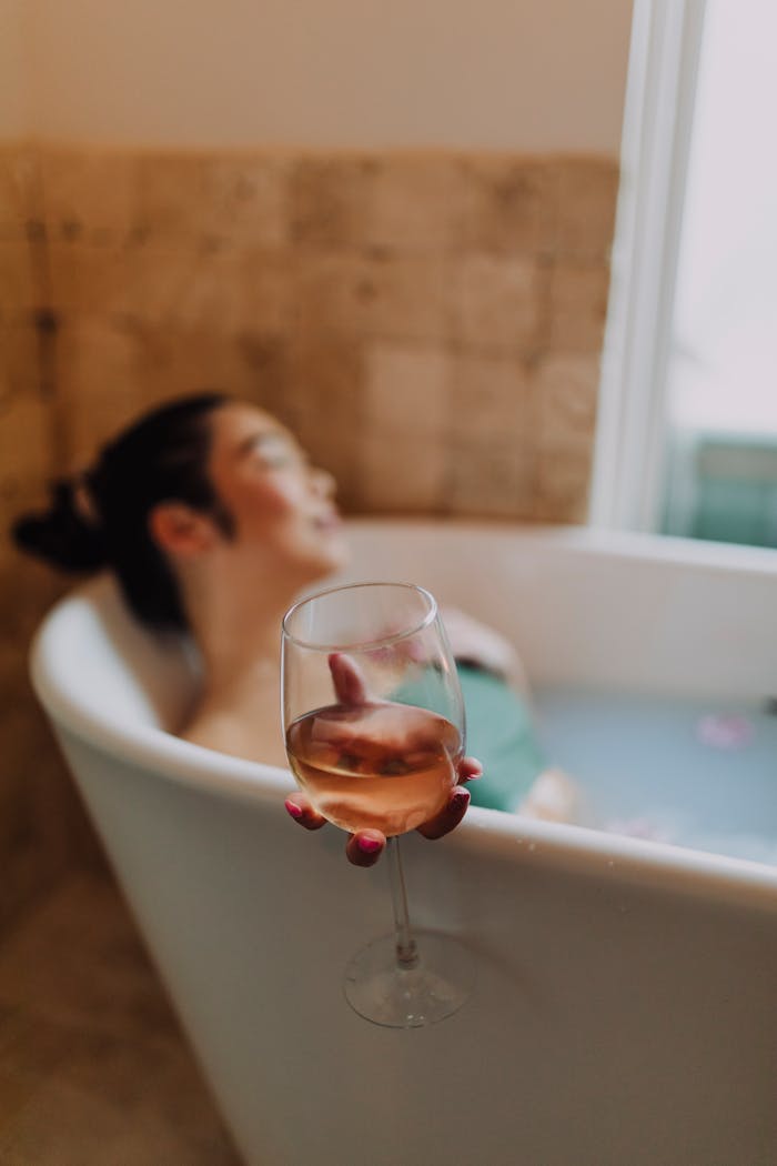 Woman in White Ceramic Bathtub Holding Clear Drinking Glass